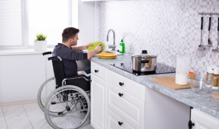 Handicapped Man Cleaning Dishes In Kitchen